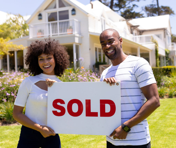couple holding a sold house board 